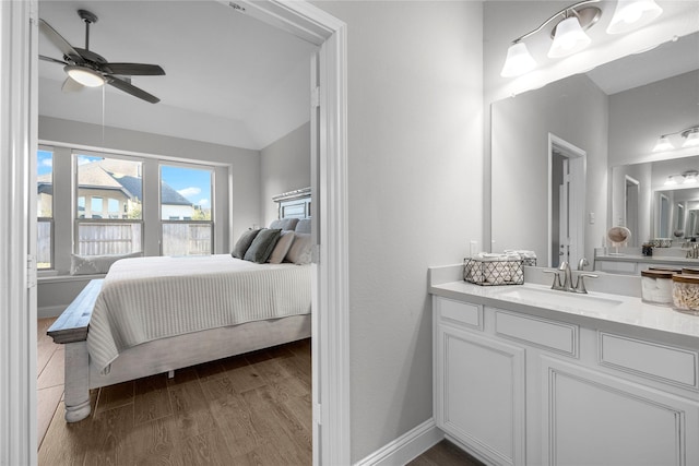 bedroom featuring connected bathroom, sink, hardwood / wood-style flooring, and ceiling fan