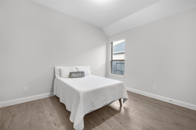 bedroom featuring hardwood / wood-style floors and vaulted ceiling