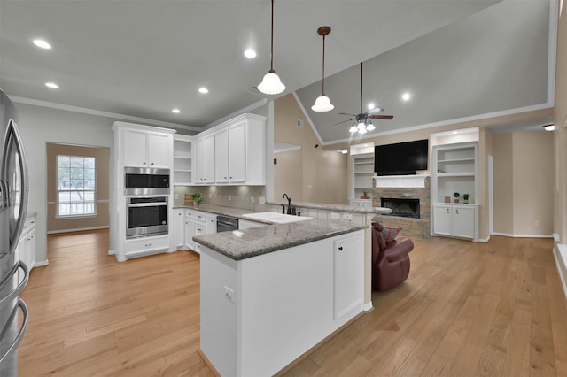 kitchen with sink, white cabinets, hanging light fixtures, kitchen peninsula, and stainless steel appliances