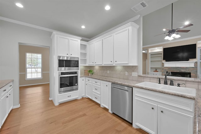kitchen with white cabinetry, sink, ornamental molding, light hardwood / wood-style floors, and stainless steel appliances