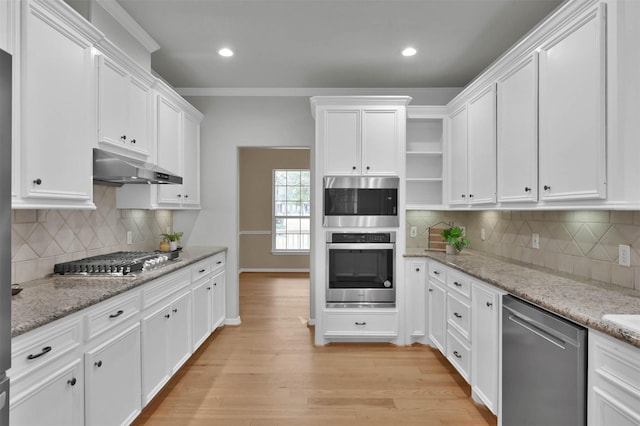kitchen with stainless steel appliances, white cabinetry, and light stone countertops