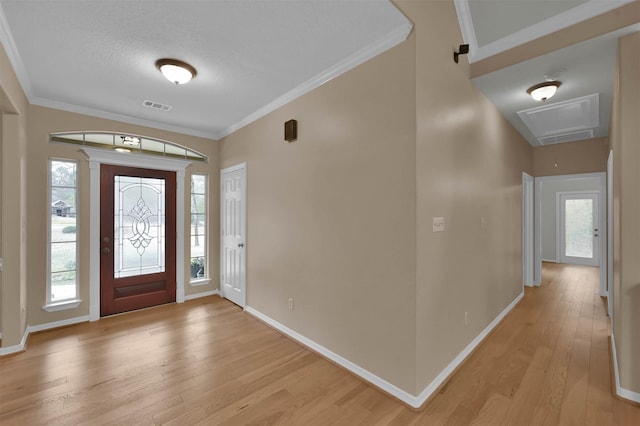 foyer with ornamental molding, light hardwood / wood-style floors, and a healthy amount of sunlight