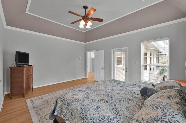 bedroom with a raised ceiling, ornamental molding, ceiling fan, and light wood-type flooring