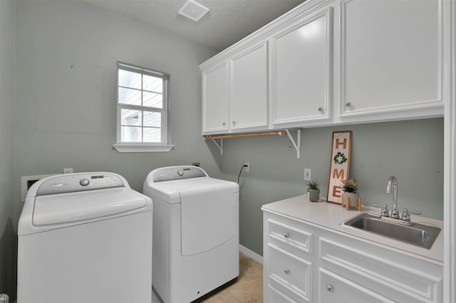laundry area featuring sink, cabinets, light tile patterned floors, washing machine and clothes dryer, and a textured ceiling