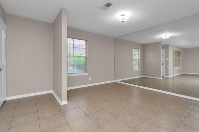 spare room featuring a wealth of natural light and light tile patterned floors