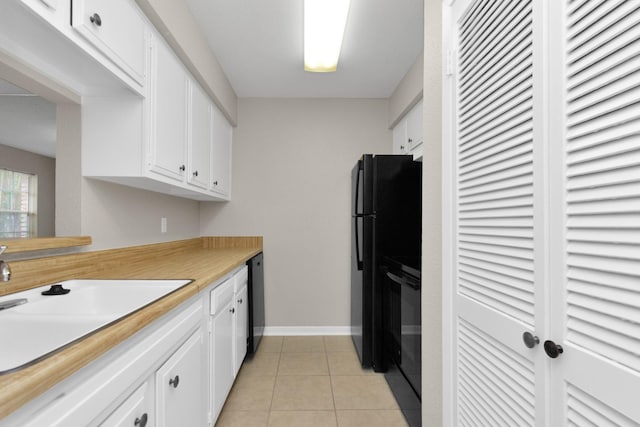 kitchen featuring light tile patterned floors, black appliances, sink, and white cabinets