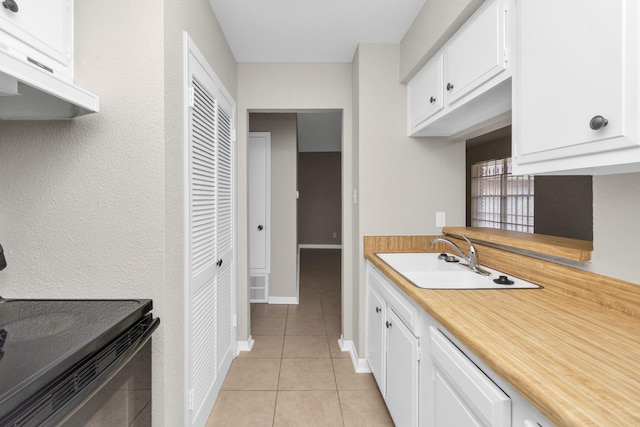 kitchen with black range with electric cooktop, light tile patterned floors, sink, and white cabinets