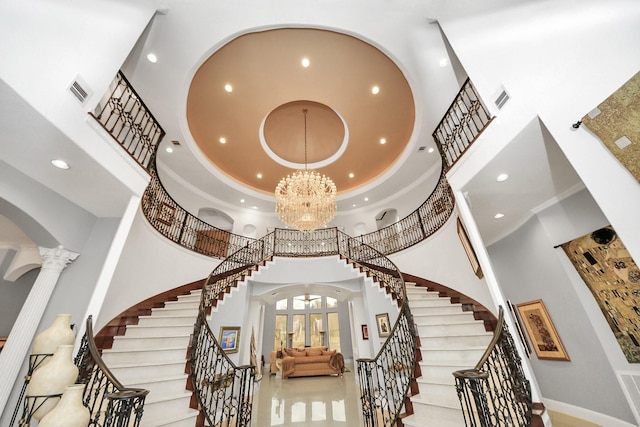 entryway featuring an inviting chandelier, crown molding, decorative columns, and a high ceiling