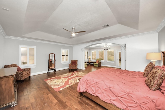 bedroom featuring a raised ceiling, ornamental molding, dark hardwood / wood-style floors, and decorative columns