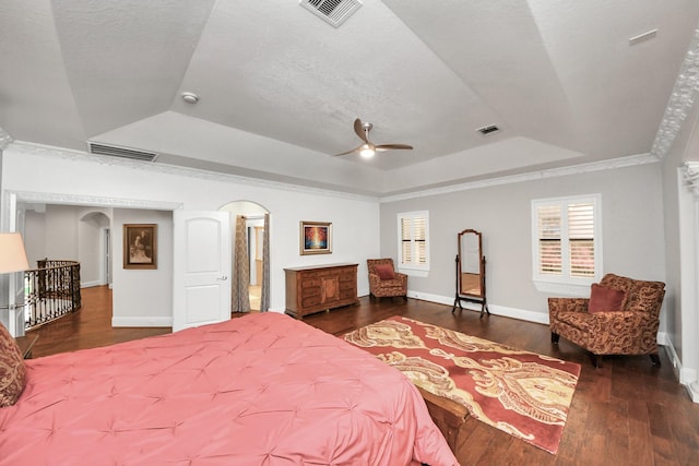 bedroom featuring crown molding, dark hardwood / wood-style floors, a raised ceiling, and a textured ceiling