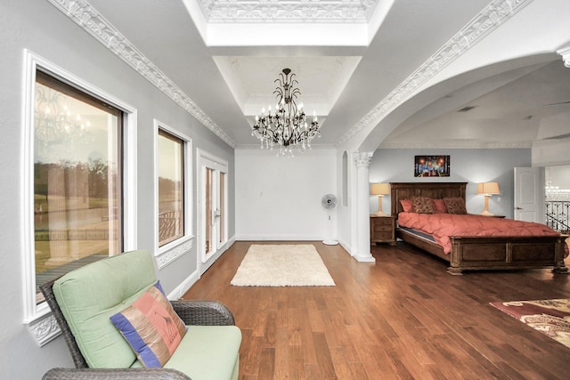 bedroom featuring a raised ceiling, crown molding, dark hardwood / wood-style floors, and ornate columns