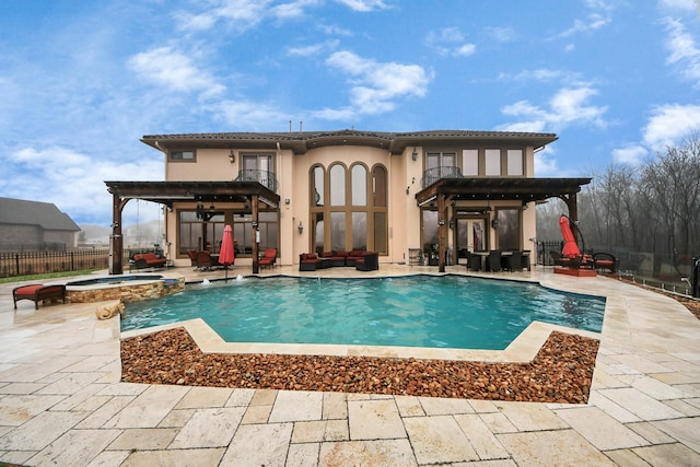 back of property with ceiling fan, a balcony, a pool with hot tub, and a patio