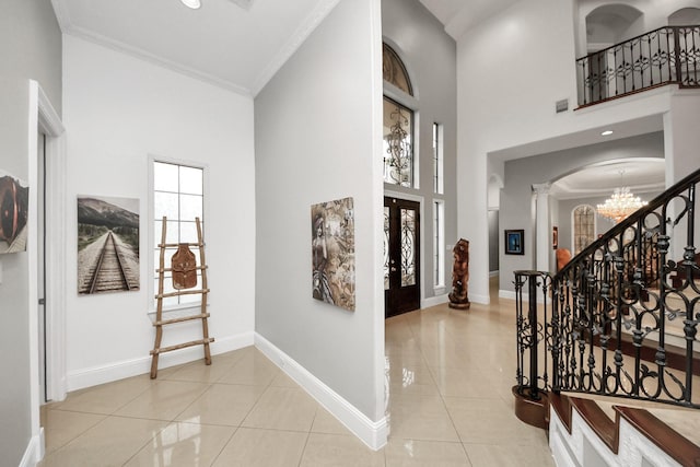 tiled entrance foyer with plenty of natural light, ornamental molding, and a high ceiling