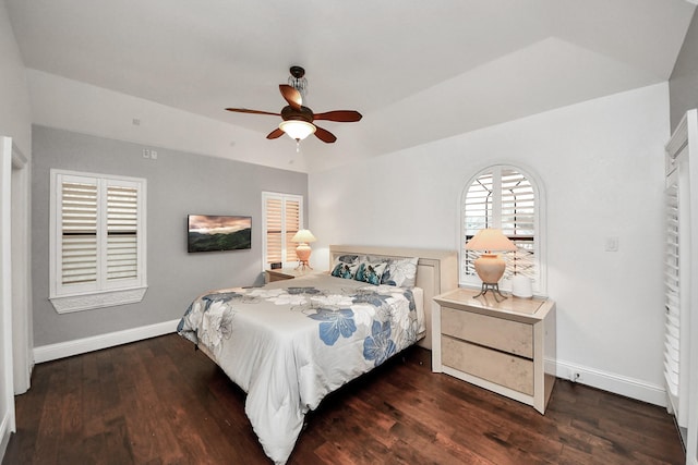 bedroom with dark hardwood / wood-style flooring, a raised ceiling, and ceiling fan