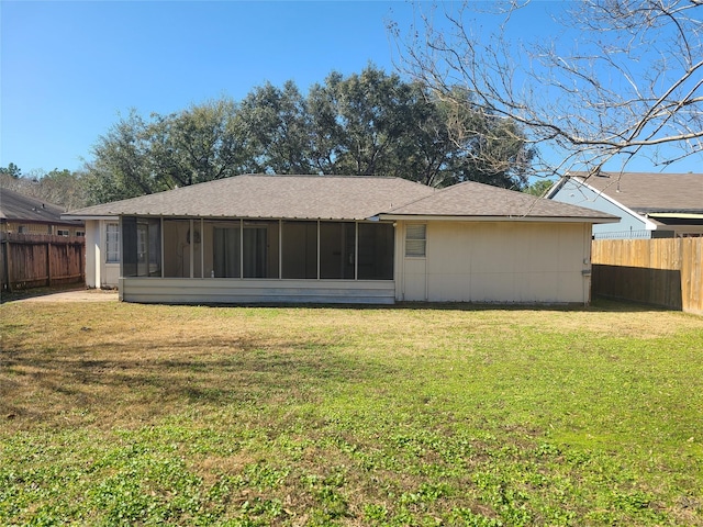 rear view of house featuring a yard and a sunroom