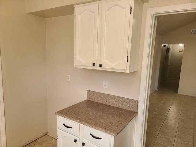 kitchen featuring white cabinetry, lofted ceiling, and light tile patterned floors