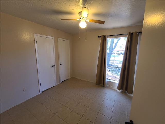 tiled spare room with ceiling fan and a textured ceiling