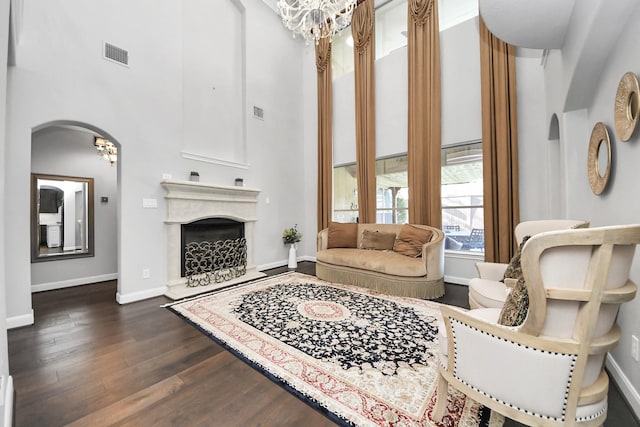 living room with a fireplace, dark hardwood / wood-style floors, a chandelier, and a towering ceiling