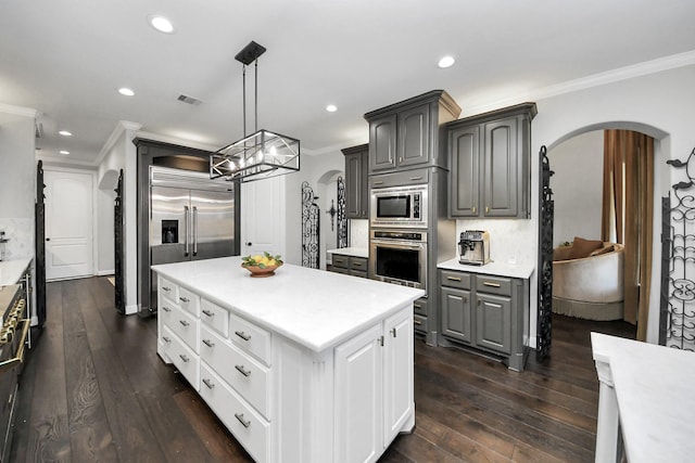 kitchen with gray cabinets, white cabinetry, decorative backsplash, built in appliances, and crown molding