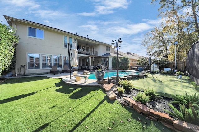 back of house with a balcony, a fenced in pool, a patio area, and a lawn