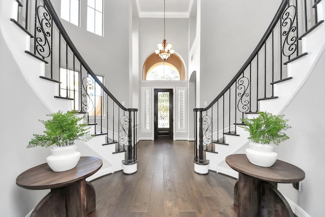 foyer entrance featuring an inviting chandelier, crown molding, dark hardwood / wood-style floors, and a high ceiling