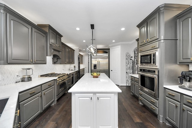 kitchen with dark wood-type flooring, gray cabinetry, built in appliances, a kitchen island, and decorative backsplash