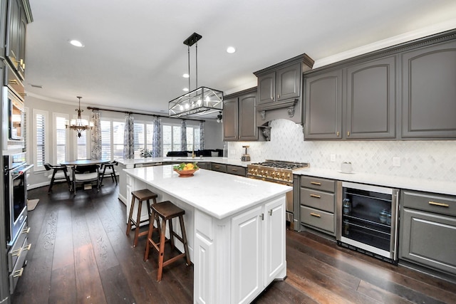 kitchen featuring gray cabinetry, high end range, a kitchen island, pendant lighting, and beverage cooler