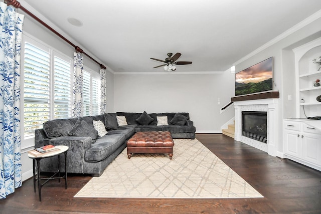 living room with crown molding, dark wood-type flooring, built in shelves, and ceiling fan