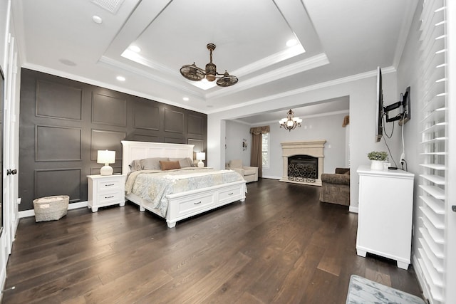 bedroom featuring an inviting chandelier, a tray ceiling, dark wood-type flooring, and ornamental molding