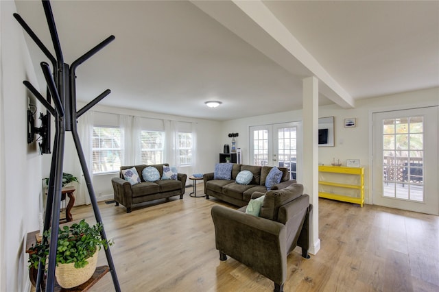 living room with beam ceiling, plenty of natural light, french doors, and light wood-type flooring