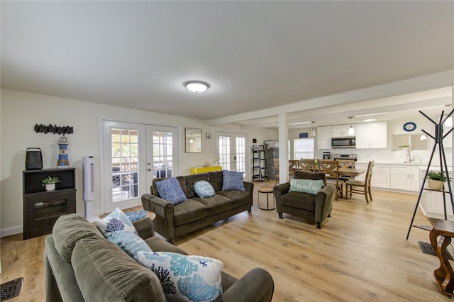 living room featuring french doors, sink, and light hardwood / wood-style floors