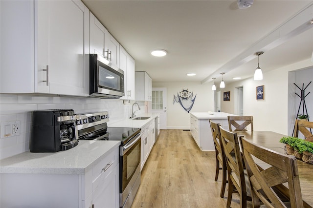 kitchen featuring white cabinetry, stainless steel appliances, decorative light fixtures, and sink