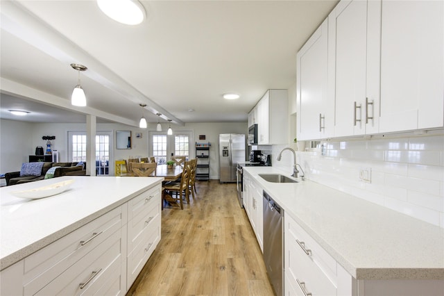 kitchen featuring sink, white cabinetry, decorative light fixtures, appliances with stainless steel finishes, and backsplash