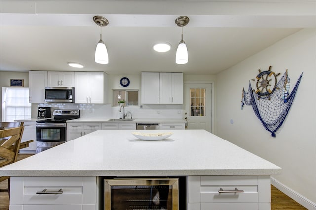 kitchen with wine cooler, sink, a center island, appliances with stainless steel finishes, and white cabinets