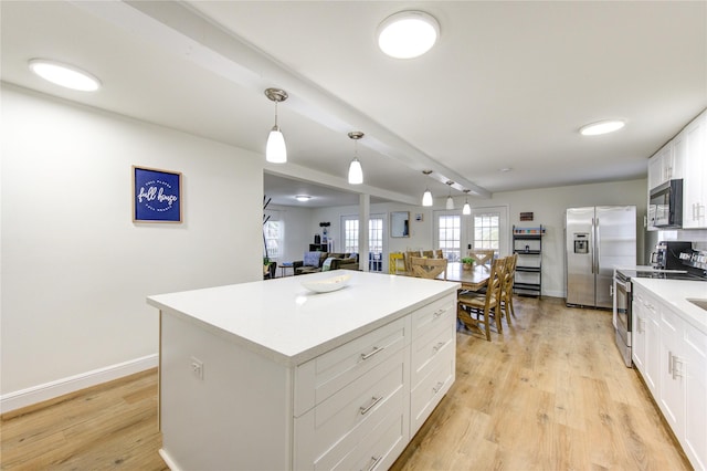 kitchen featuring white cabinetry, hanging light fixtures, stainless steel appliances, light hardwood / wood-style floors, and a kitchen island