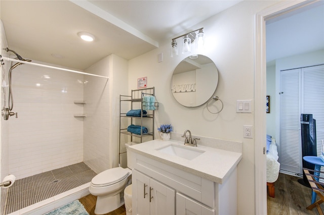 bathroom with vanity, hardwood / wood-style flooring, toilet, and a tile shower