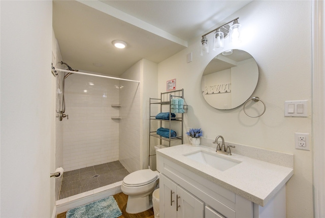 bathroom featuring vanity, toilet, hardwood / wood-style floors, and a tile shower