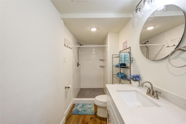 bathroom featuring a tile shower, vanity, hardwood / wood-style flooring, and toilet