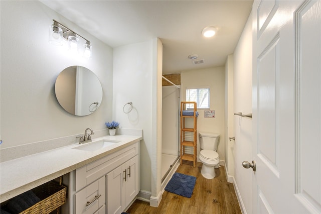 bathroom featuring walk in shower, vanity, toilet, and hardwood / wood-style floors