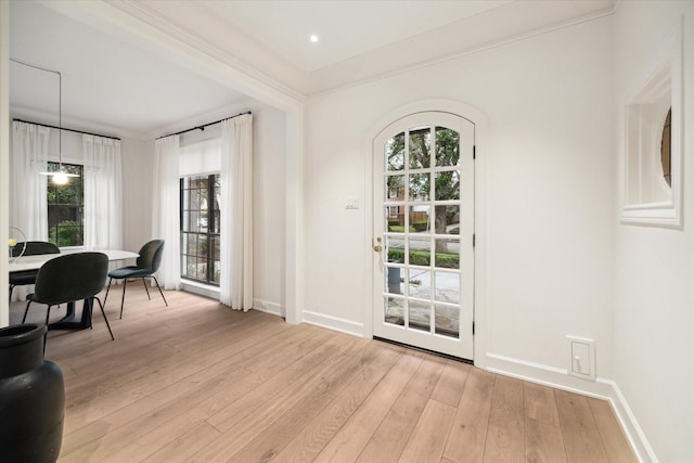 doorway with crown molding, light hardwood / wood-style flooring, and a wealth of natural light