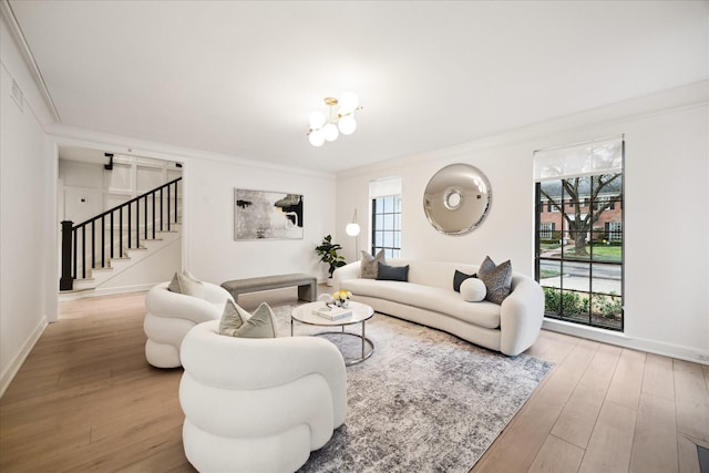 living room with hardwood / wood-style floors, a notable chandelier, a wealth of natural light, and ornamental molding