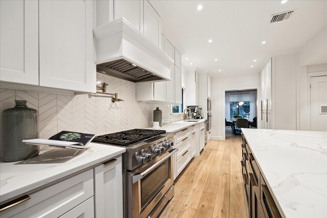 kitchen featuring white cabinetry, premium range hood, stainless steel range, and light stone counters