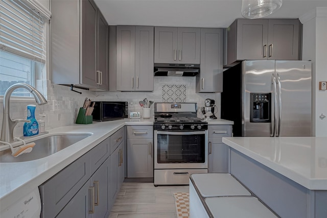 kitchen with tasteful backsplash, sink, gray cabinetry, and appliances with stainless steel finishes