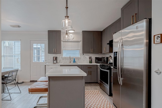 kitchen with pendant lighting, sink, a kitchen bar, a center island, and stainless steel appliances