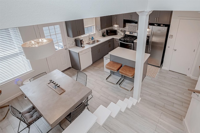 kitchen featuring appliances with stainless steel finishes, sink, decorative backsplash, a center island, and dark brown cabinets