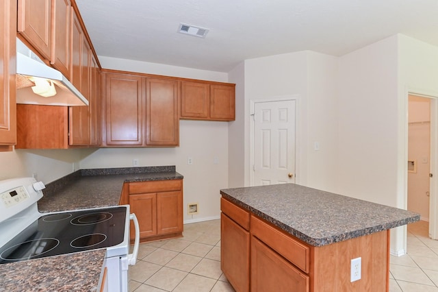 kitchen with white electric range oven, a kitchen island, and light tile patterned floors