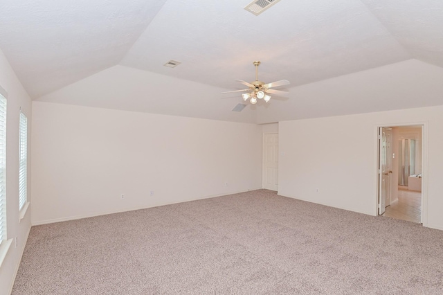 spare room with ceiling fan, vaulted ceiling, and light carpet