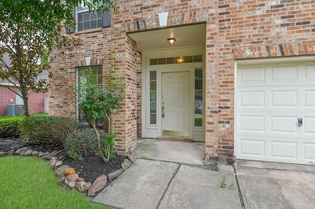 view of exterior entry with a garage and central AC unit