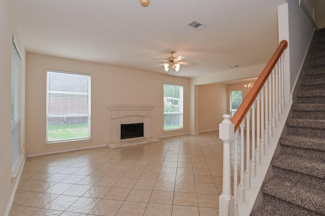 unfurnished living room with a premium fireplace, ceiling fan, and light tile patterned flooring