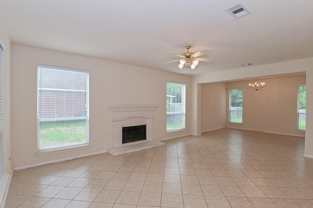 unfurnished living room with a fireplace, ceiling fan with notable chandelier, and light tile patterned floors